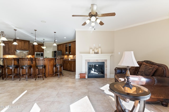 living area with a tile fireplace, light tile patterned floors, crown molding, and ceiling fan