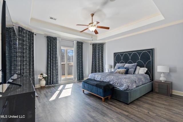 bedroom with ornamental molding, a raised ceiling, baseboards, and wood finished floors