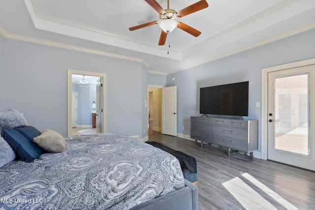 bedroom with crown molding, baseboards, a raised ceiling, and wood finished floors