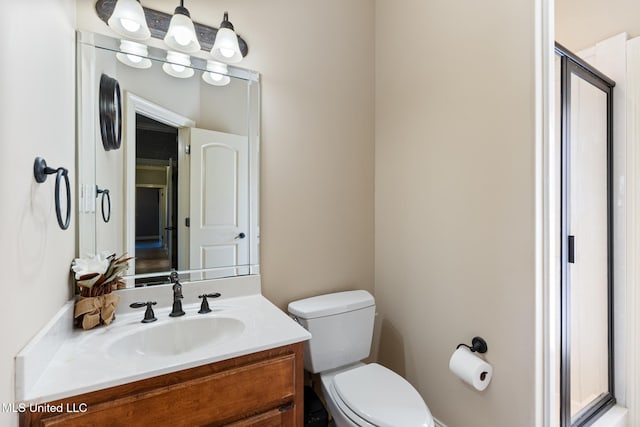 bathroom featuring toilet, a shower with shower door, and vanity