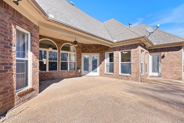 exterior space featuring ceiling fan, french doors, roof with shingles, and brick siding