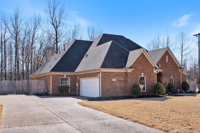 view of front of property featuring driveway, brick siding, an attached garage, and fence