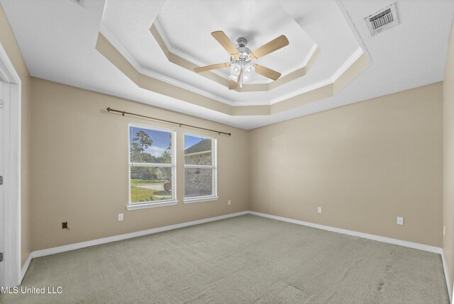 carpeted empty room featuring ornamental molding, ceiling fan, and a raised ceiling