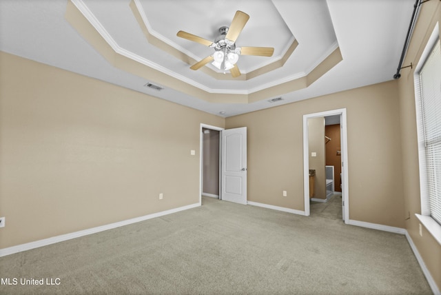 unfurnished bedroom with ceiling fan, a tray ceiling, and light colored carpet