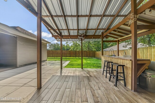 wooden deck featuring an outdoor bar, a lawn, ceiling fan, and a patio