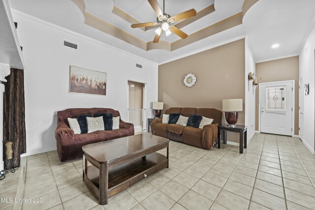 living room with a raised ceiling, ceiling fan, light tile patterned floors, and crown molding