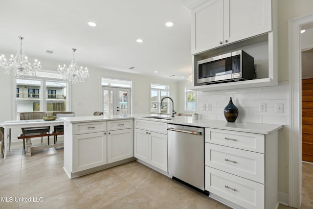 kitchen with appliances with stainless steel finishes, decorative light fixtures, sink, and white cabinets