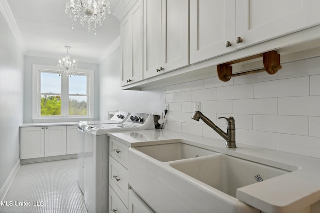 washroom with sink, cabinets, ornamental molding, washing machine and clothes dryer, and a notable chandelier