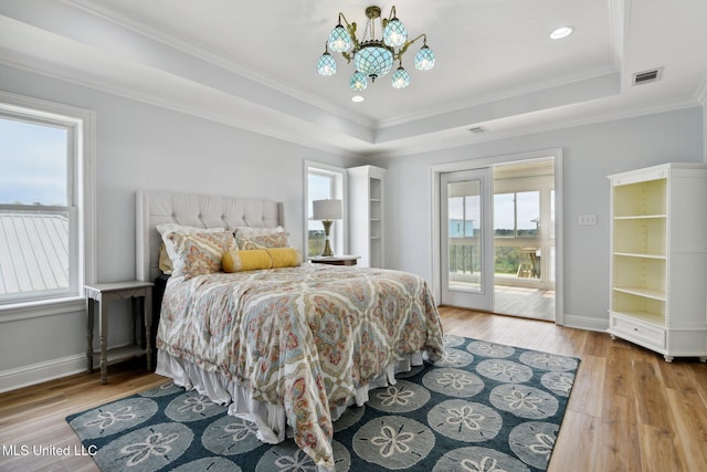 bedroom featuring a raised ceiling, a chandelier, access to exterior, and light wood-type flooring