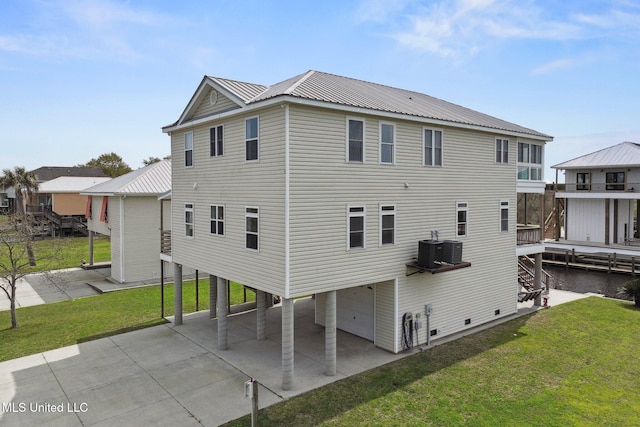 rear view of house featuring a garage, central AC unit, and a lawn