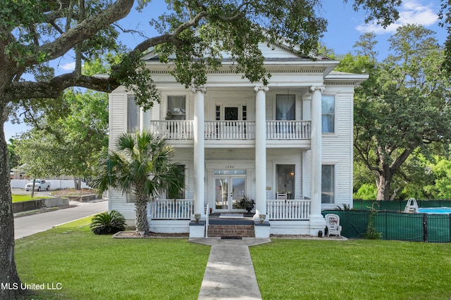 greek revival house with a front yard, covered porch, and a balcony