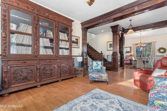 living room featuring ornate columns, a notable chandelier, beam ceiling, and light wood-type flooring