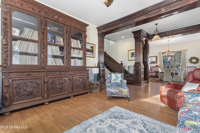 living area with wood finished floors, ornate columns, stairway, and a chandelier