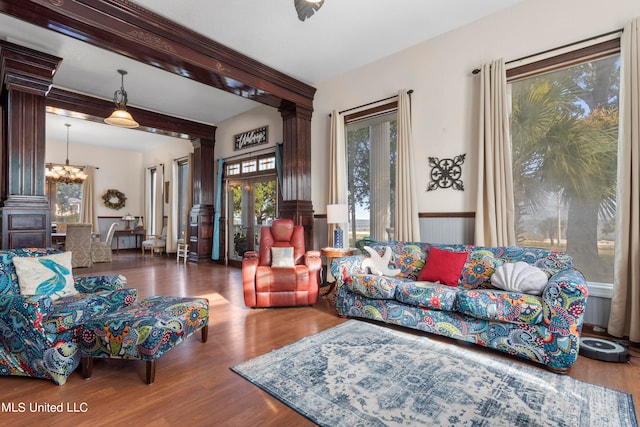 living room with dark wood-type flooring, ornate columns, a notable chandelier, and beam ceiling