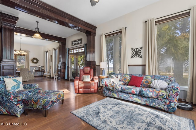 living room featuring a chandelier, wood finished floors, decorative columns, and beam ceiling