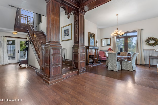 dining space with french doors, beamed ceiling, dark wood-type flooring, decorative columns, and a notable chandelier