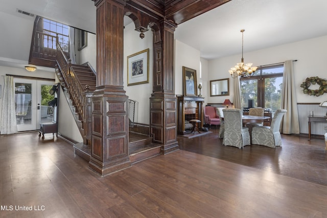 dining room with decorative columns, dark wood-style flooring, stairway, french doors, and a chandelier