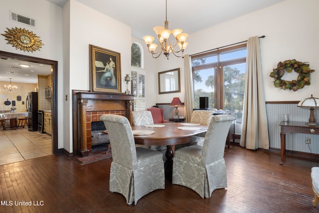 dining room featuring dark wood-type flooring, a notable chandelier, and a fireplace