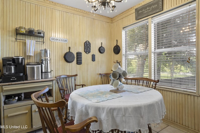 tiled dining space featuring a chandelier and wooden walls