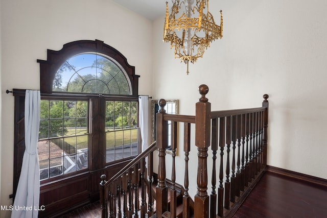 stairs with wood-type flooring and an inviting chandelier