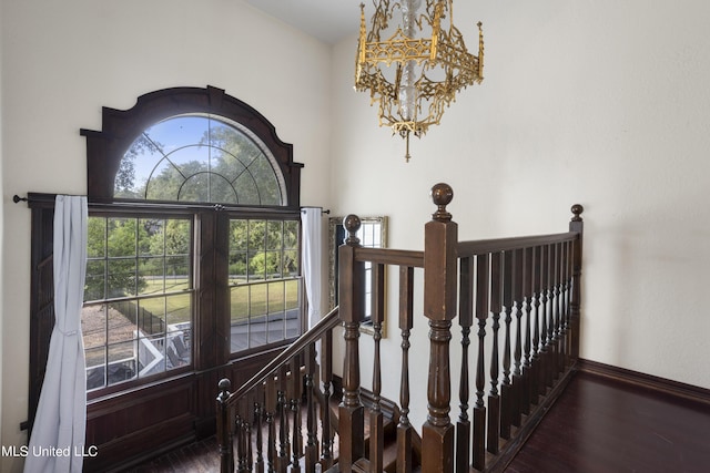 staircase featuring wood finished floors, baseboards, and a chandelier
