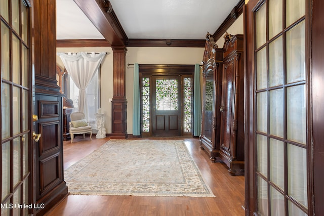 entryway featuring hardwood / wood-style floors, decorative columns, and crown molding