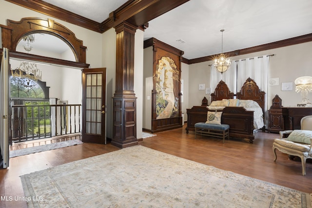 bedroom featuring a chandelier, wood finished floors, ornamental molding, and ornate columns