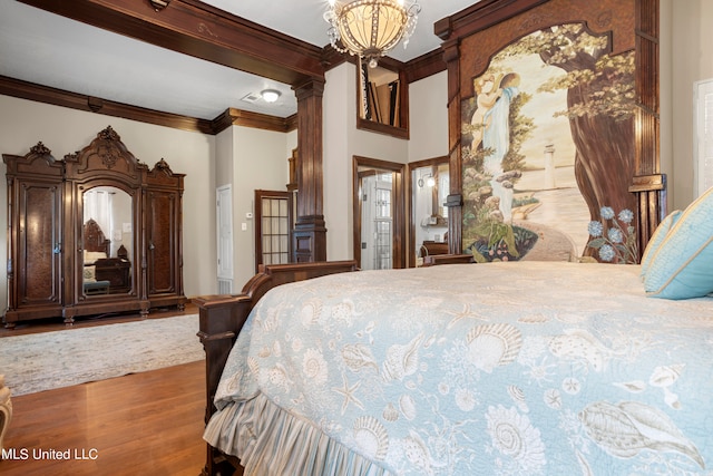 bedroom featuring ornamental molding, a notable chandelier, and hardwood / wood-style flooring