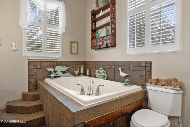 bathroom with a healthy amount of sunlight, toilet, and a relaxing tiled tub