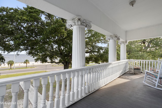 balcony with covered porch and a water view