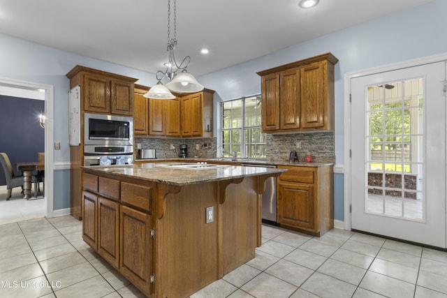 12880 Coles Cv, Gulfport, MS 39503 - kitchen featuring stainless steel appliances, light tile patterned floors, a kitchen island, dark stone countertops, and decorative backsplash