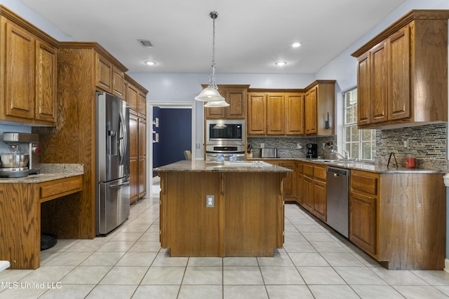 12880 Coles Cv, Gulfport, MS 39503 - kitchen featuring appliances with stainless steel finishes, brown cabinetry, backsplash, a kitchen island, and a sink