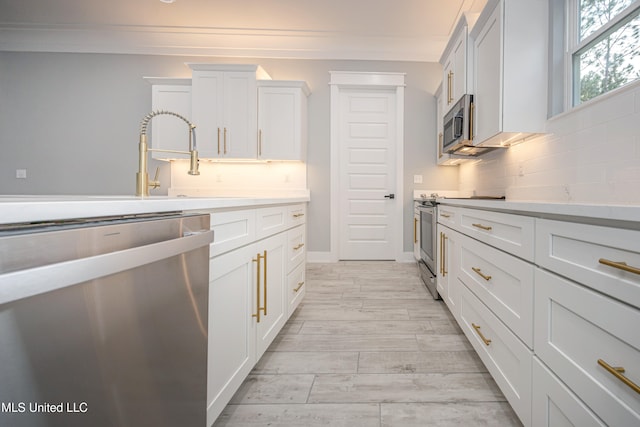 kitchen featuring ornamental molding, white cabinetry, appliances with stainless steel finishes, light hardwood / wood-style floors, and tasteful backsplash