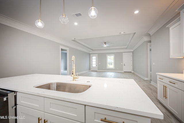 kitchen featuring a kitchen island with sink, sink, pendant lighting, light wood-type flooring, and light stone counters