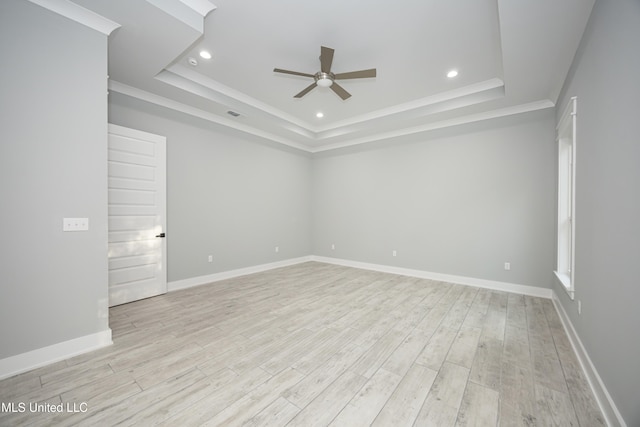 unfurnished room with a tray ceiling, light wood-type flooring, and ceiling fan