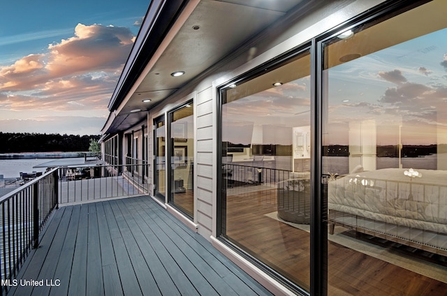 deck at dusk featuring a water view