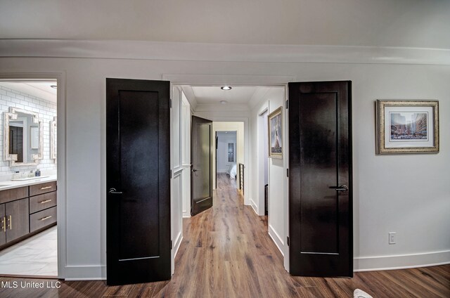 corridor featuring sink and light hardwood / wood-style flooring