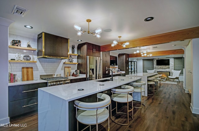 kitchen with stainless steel appliances, decorative backsplash, an island with sink, and dark hardwood / wood-style floors