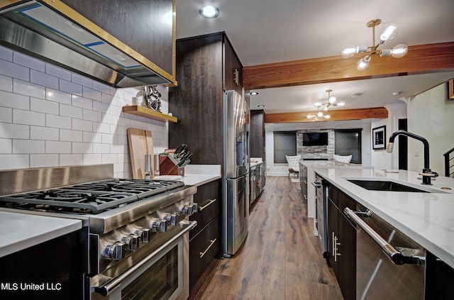 kitchen featuring appliances with stainless steel finishes, an inviting chandelier, dark wood-type flooring, pendant lighting, and sink