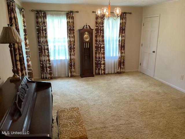 unfurnished room featuring an inviting chandelier and carpet