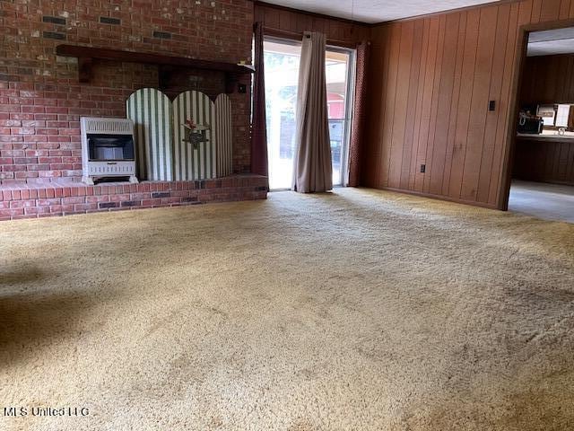 unfurnished living room with wood walls, carpet flooring, and heating unit