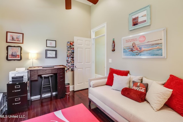 living area with dark wood-type flooring, a ceiling fan, a high ceiling, and baseboards