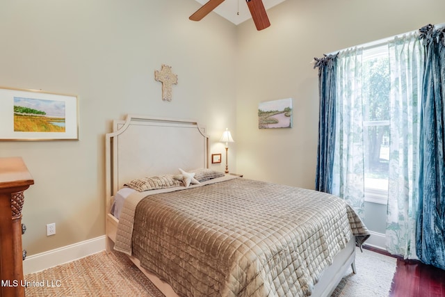 bedroom featuring multiple windows, baseboards, wood finished floors, and ceiling fan