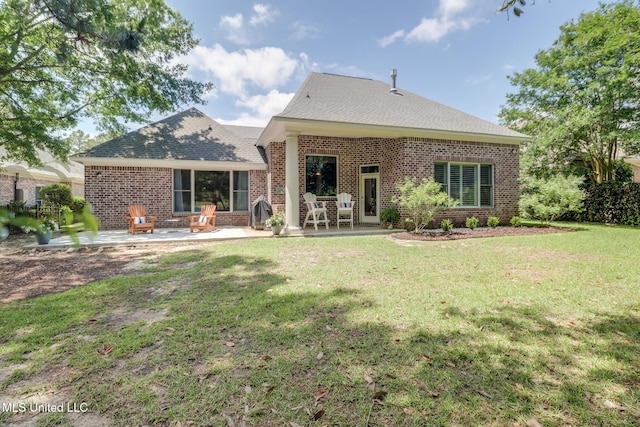 back of property featuring brick siding, a patio, a yard, and roof with shingles
