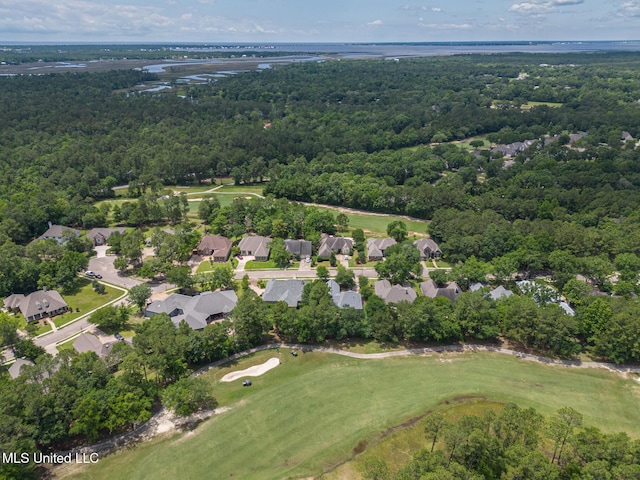 aerial view of property and surrounding area featuring a heavily wooded area, a golf club, nearby suburban area, and a nearby body of water