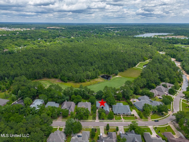 aerial view of property's location featuring a forest, nearby suburban area, and a nearby body of water