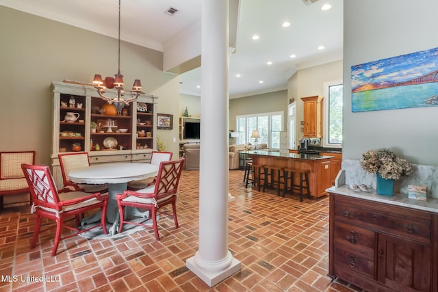 dining space featuring ornamental molding, brick floors, recessed lighting, a chandelier, and decorative columns