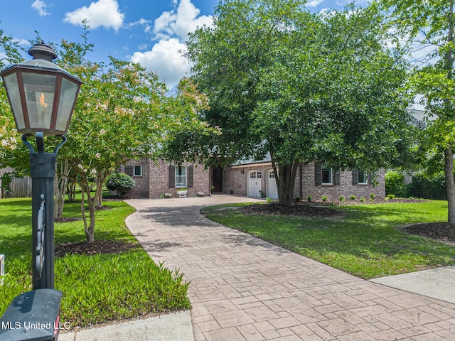 view of front of house with decorative driveway, brick siding, a front lawn, and an attached garage