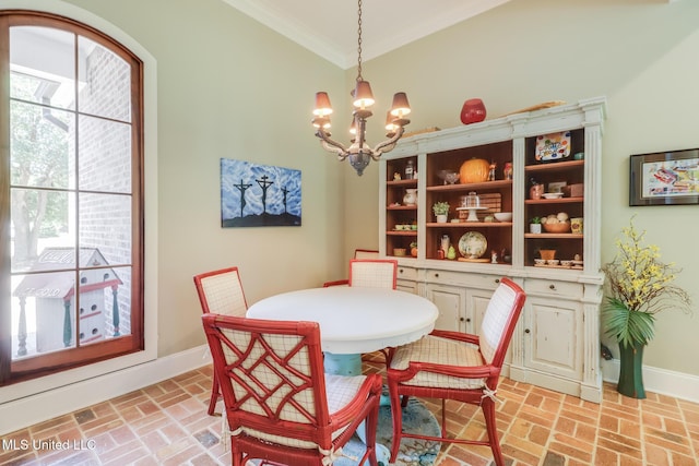 dining area featuring brick floors, ornamental molding, a chandelier, and baseboards