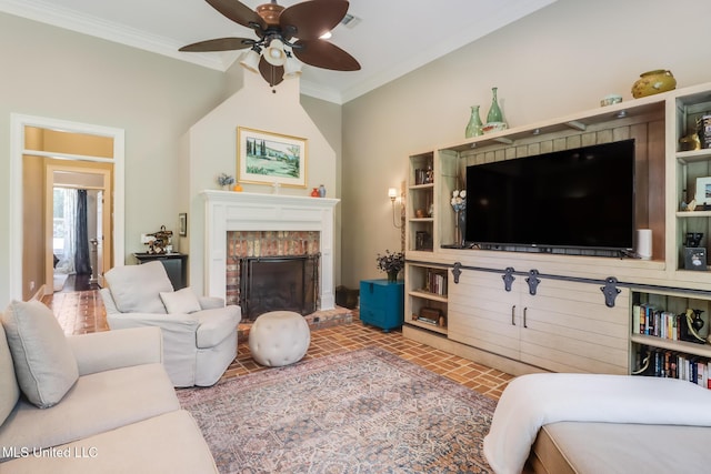 living room with a ceiling fan, a fireplace, ornamental molding, and brick patterned floors